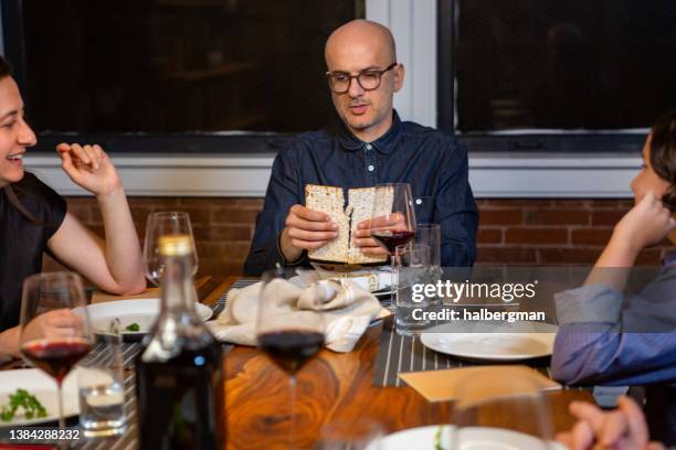 líder del seder rompiendo el medio matzo - passover seder plate fotografías e imágenes de stock