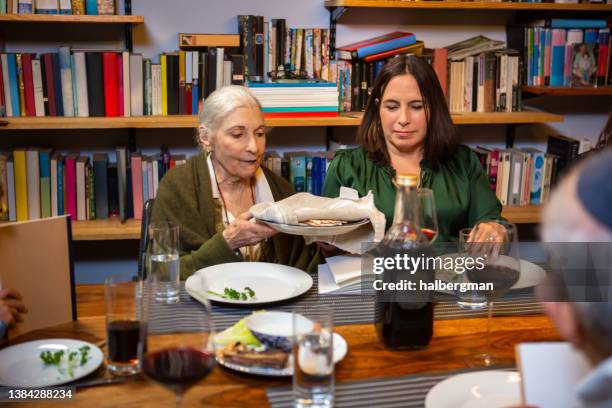 woman taking matzo from plate at family seder - seder 個照片及圖片檔