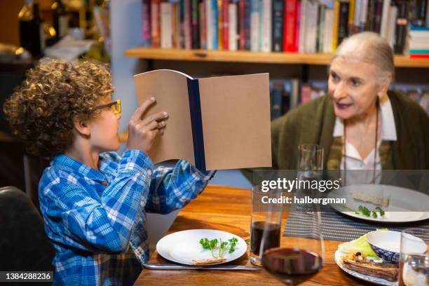 kleiner junge zeigt auf die haggada am pessach-seder - passover stock-fotos und bilder