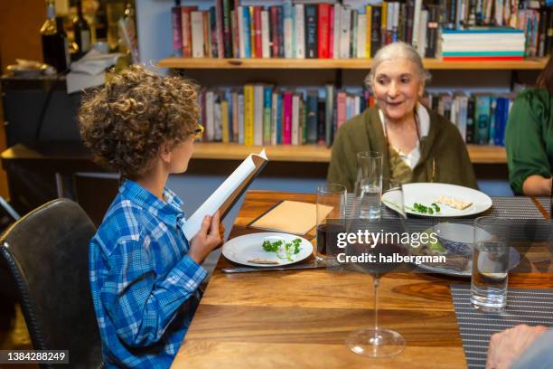 little boy reading from haggadah - pesach seder stock pictures, royalty-free photos & images