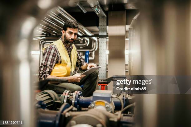 technician engineer man in uniform with tablet checking and control boiler tanks and liquid pipeline in production line at factory - boiler engineer stockfoto's en -beelden