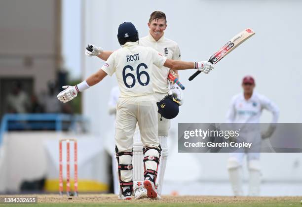 Zak Crawley of England celebrates with captain Joe Root afterreaching his century during day four of the first test match between West Indies and...