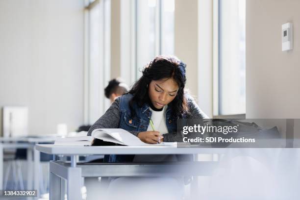 focused young woman - student reading book stockfoto's en -beelden