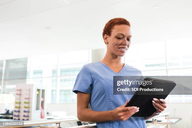female physical therapist uses digital tablet to plan patient schedule - nurse ipad stockfoto's en -beelden