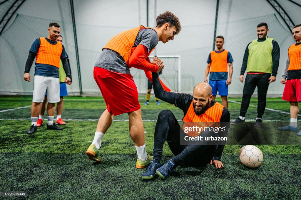Soccer player helping his rival to stand up