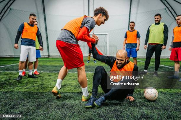 jogador de futebol ajudando seu rival a se levantar - rivalidade - fotografias e filmes do acervo