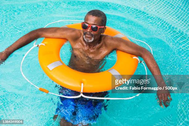 happy senior man at the swimming pool - man on float stock pictures, royalty-free photos & images