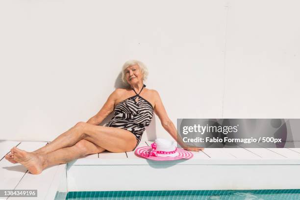 happy senior woman at the swimming pool - old woman in swimsuit stock-fotos und bilder