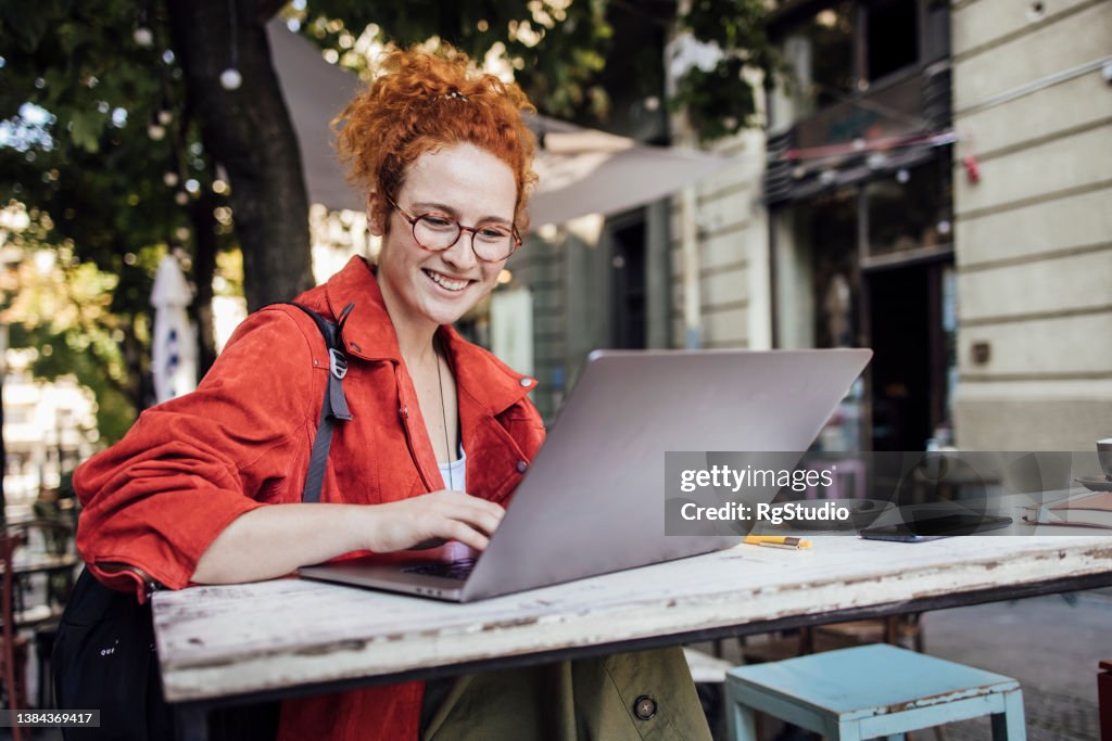 Beautiful, cheerful girl enjoying at the cafe and surfing the net
