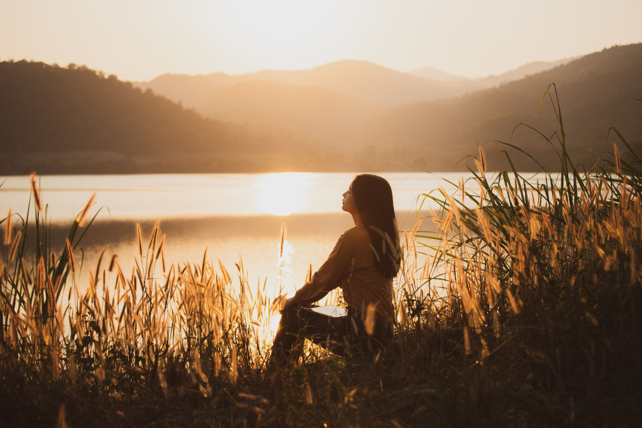 Rear view of a woman tourist sitting at a walkway near the reservoir. Rear view of a woman tourist sitting at a walkway near the reservoir.