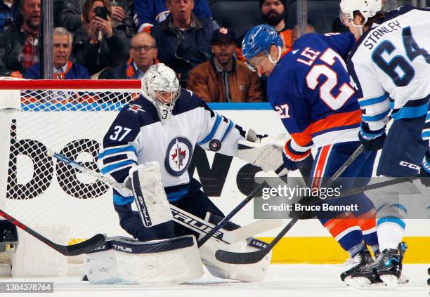 Connor Hellebuyck of the Winnipeg Jets makes the first period save on Anders Lee of the New York Islanders at the UBS Arena on March 11, 2022 in...