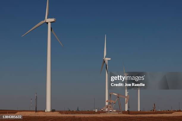 An oil pumpjack works near wind turbines in the Permian Basin oil field on March 11, 2022 in Stanton, Texas. United States President Joe Biden...