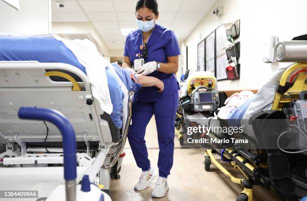 Lab technician Alejandra Sanchez cares for a patient in the Emergency Department at Providence St. Mary Medical Center on March 11, 2022 in Apple...