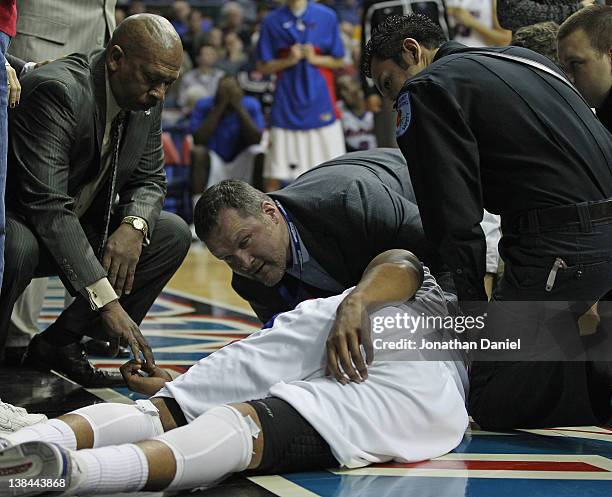 Head coach Oliver Purnell of the DePaul Blue Demons holds the hand of Moses Morgan after he landed on his head falling over Darius Johnson-Odom of...