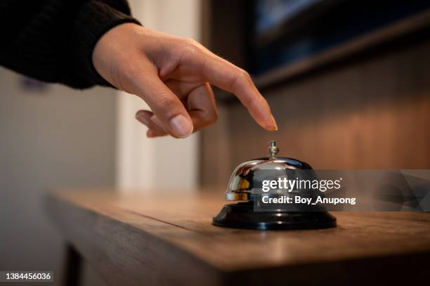 close up of someone hand trying to call hotel reception by ringing front desk bell. - ベル ストックフォトと画像