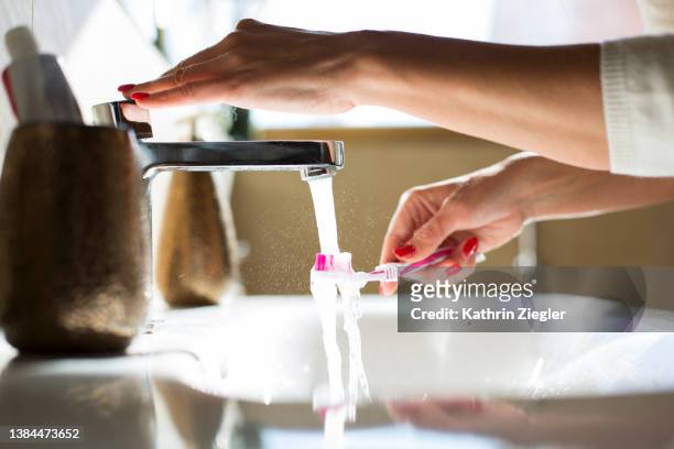 woman rinsing her toothbrush, close-up of hands - zähne putzen frau stock-fotos und bilder