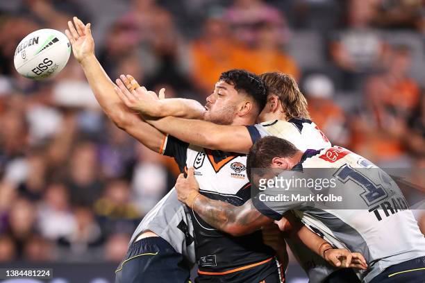 David Nofoaluma of the Tigers passes as he is tackled during the round one NRL match between the Wests Tigers and the Melbourne Storm at CommBank...