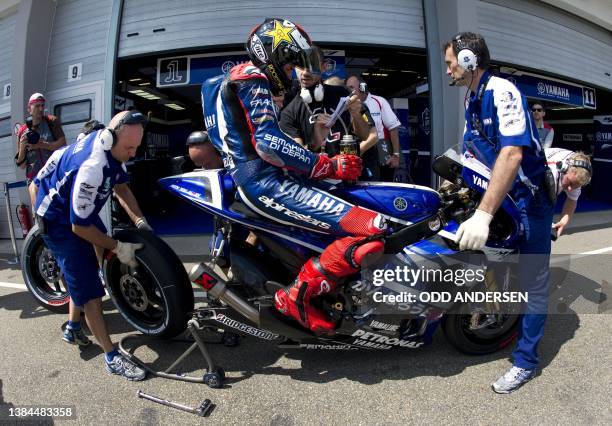 Yamaha rider Jorge Lorenzo of Spain sits on his bike as mechanics change the wheel during the qualifying of the Moto Grand Prix at the Sachsenring...