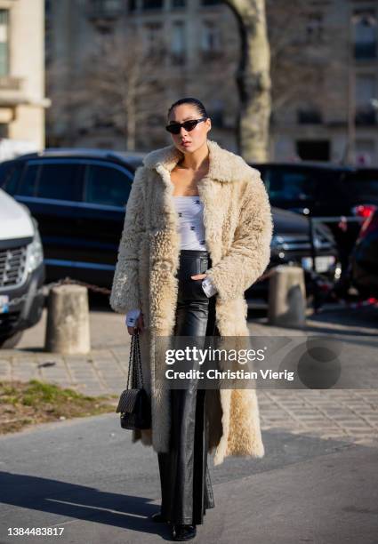 Guest is seen wearing beige faux fur coat, black leather pants, Chanel bag, off shoulder topoutside Chanel during Paris Fashion Week - Womenswear F/W...