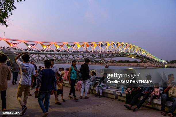 People sit along the banks of Sabarmati River in Ahmedabad on July 2, 2023.