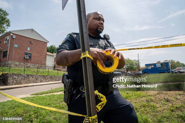 Baltimore Police officer hangs police tape at the site of a mass shooting in the Brooklyn Homes neighborhood on July 2, 2023 in Baltimore, Maryland....