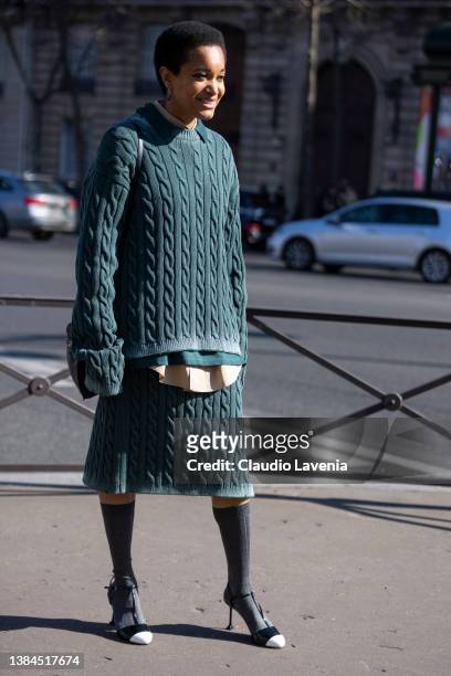 Tamu McPherson wearing a green Miu Miu sweater with matching midi skirt, grey socks and black and white heels, is seen outside Miu Miu, during Paris...