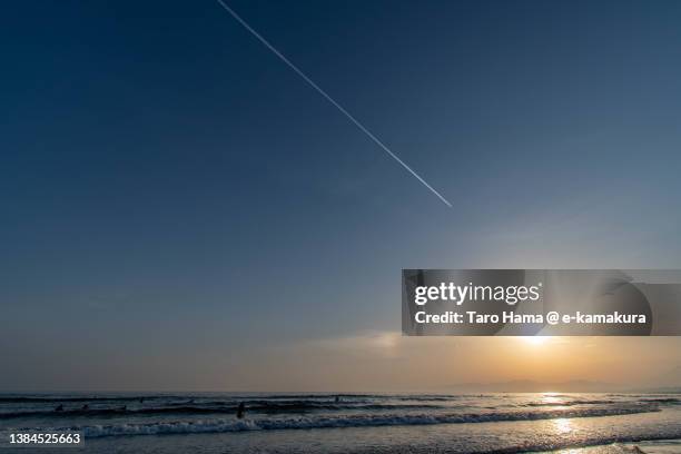 the airplane flying over the sunset beach in kanagawa of japan - sunset contrail stock pictures, royalty-free photos & images