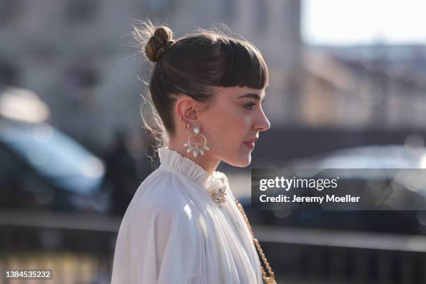 Laurence Fortincote seen wearing silver pearl earrings from Chanel, a white blouse, a gold pearl and rhinestone brooch and a black handbag from...