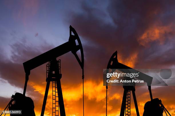 oil pump on a sunset background. world oil industry - oil pump stockfoto's en -beelden