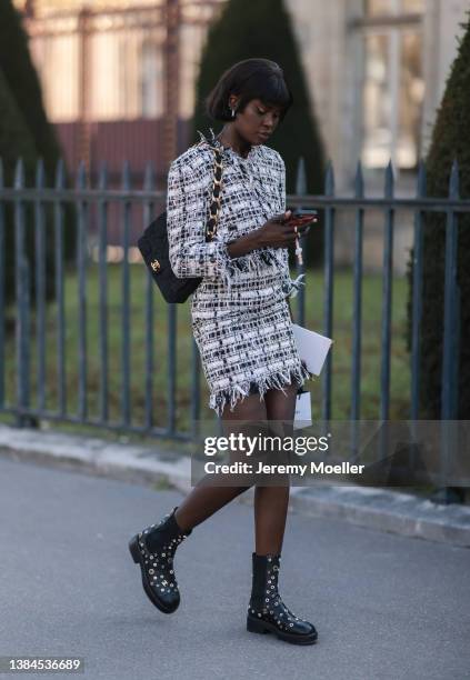 Fashion Week guest seen wearing silver earrings, a white with black and pink checkered print pattern tweed jacket from Chanel, a matching white with...