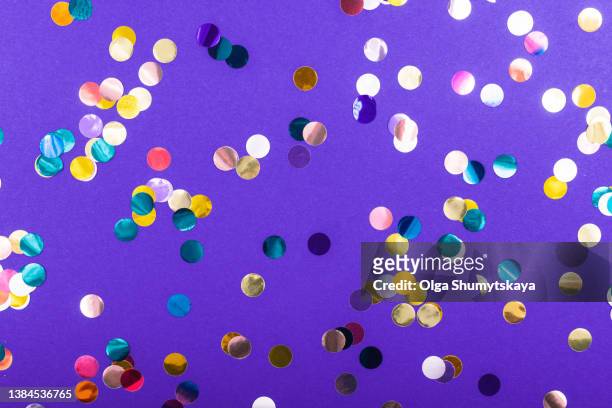 large multicolored confetti on a purple background - sequin stock pictures, royalty-free photos & images
