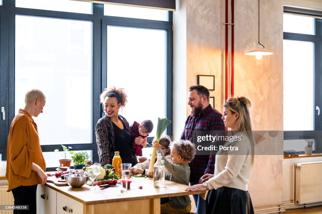 Friends talking while cooking dinner at kitchen table
