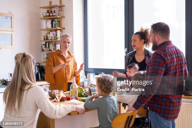 woman talking with friends while preparing dinner in kitchen - kookeiland stockfoto's en -beelden