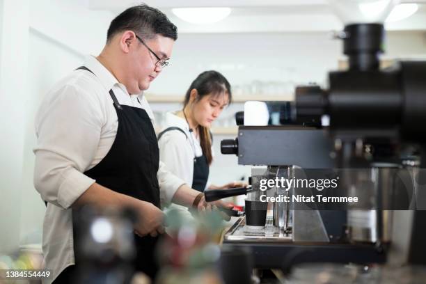 we serve coffee and snacks. side views of a male and female baristas in a coffee shop while preparing coffee drink to their customer. - chubby man shopping stock pictures, royalty-free photos & images