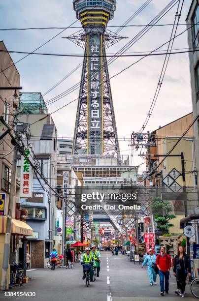 due agenti di polizia in sella a una bicicletta di fronte alla torre tsutenkaku - shinsekai osaka foto e immagini stock