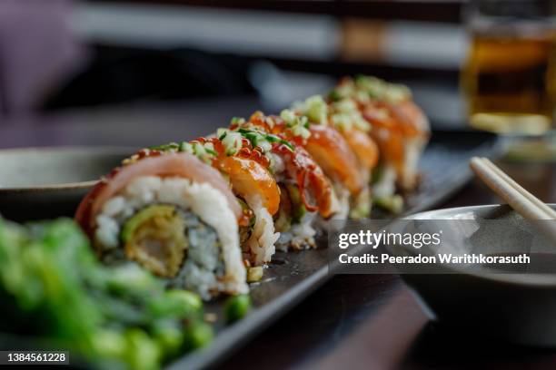 dragon roll, roll of sushi on top with fresh raw fish. - sushi restaurant stock pictures, royalty-free photos & images