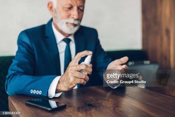 senior man at restaurant table - spray on hand stock pictures, royalty-free photos & images