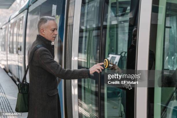 elegant businessman pushing open button entering the train, on his business trip to work - straßenbahnstrecke stock-fotos und bilder