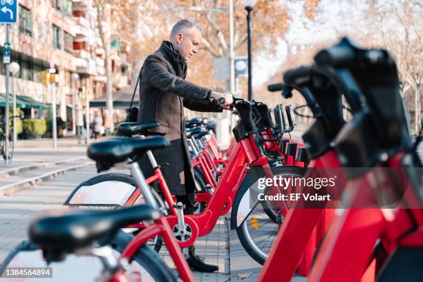 businessman choosing bike in a public bicycle service area. bicycle-sharing system concepts - commuter man europe bike stock-fotos und bilder