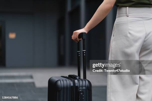 close up woman carrying suitcase in airport arrival area - suitcase close stock-fotos und bilder