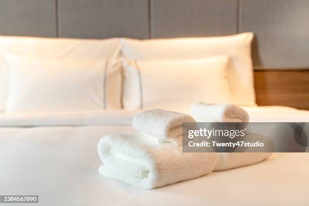 close up clean folded rolled white towels prepared on the bed in hotel room - luxury hotel room stock pictures, royalty-free photos & images