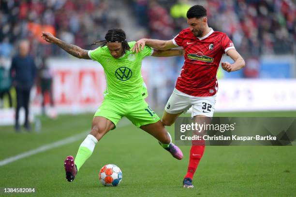 Kevin Mbabu of VfL Wolfsburg is challenged by Vincenzo Grifo of SC Freiburg during the Bundesliga match between Sport-Club Freiburg and VfL Wolfsburg...