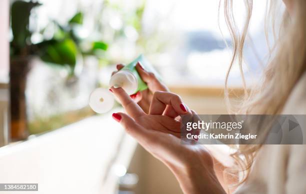 woman applying face cream, close-up of hands - cremas faciales fotografías e imágenes de stock