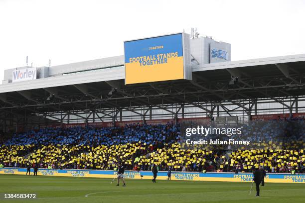 Screen displays the message "Football Stands Together" featuring a Ukrainian flag inside the stadium to indicate peace and sympathy with Ukraine...