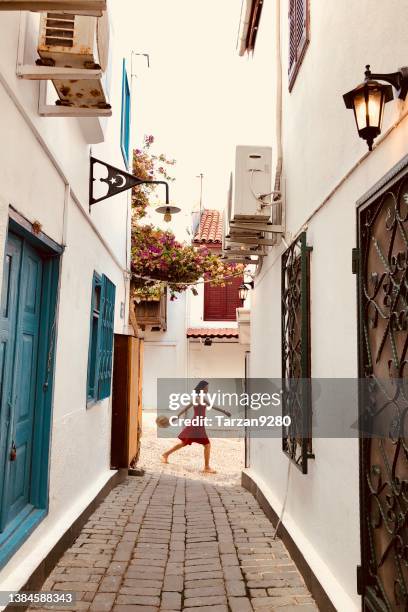 schönes und schlankes mädchen, das an der kleinen gasse in einer alten stadt in der ägäis, türkei, vorbeigeht - single lane road stock-fotos und bilder