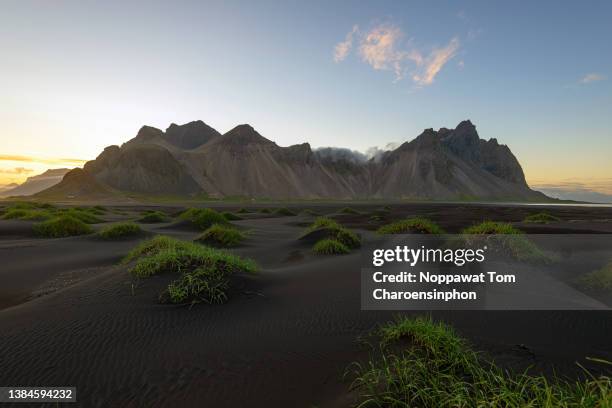 scenic view of vestrahorn mountain with black sand beach - hofn - iceland during sunset - black sand iceland stock-fotos und bilder