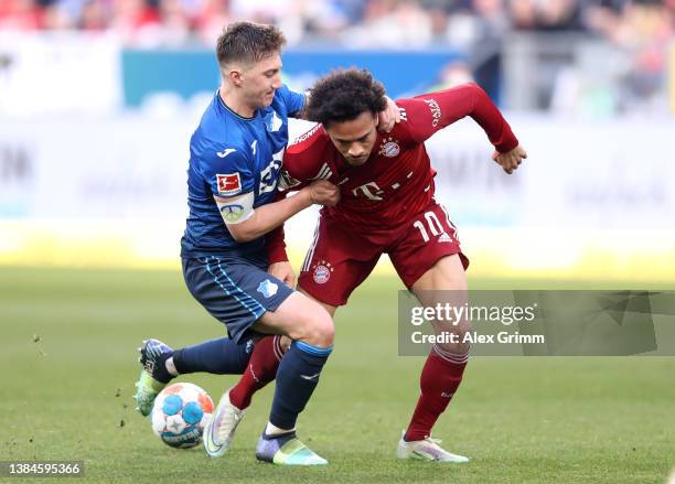 Leroy Sane of FC Bayern Muenchen is challenged by Angelo Stiller of TSG 1899 Hoffenheim during the Bundesliga match between TSG Hoffenheim and FC...