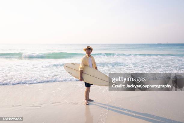 surfer with surfboard looking out to sea at sunrise - idyllic surfboard stock pictures, royalty-free photos & images