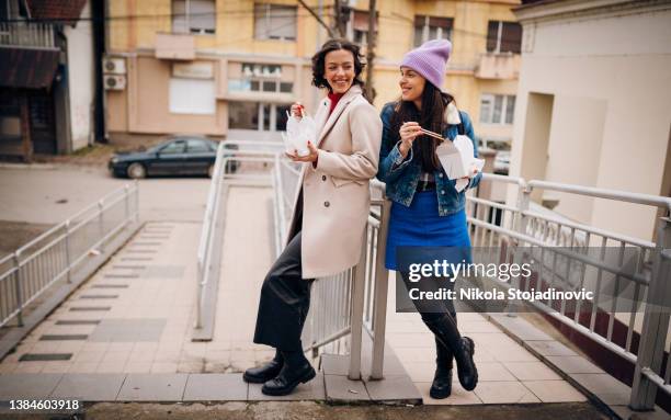 two female friends eating chinese fast food with chopsticks - chinese food stock pictures, royalty-free photos & images