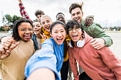 Multiracial friends taking big group selfie shot smiling at camera -Laughing young people standing outdoor and having fun - Cheerful students portrait outside school - Human resources concept